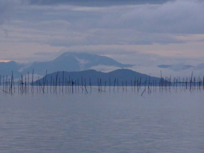 明け方の真野浜から眺めた琵琶湖北湖は曇天微風のベタナギ。視界はよくて沖島の向こうに伊吹山が見えてます（10月10日6時頃）