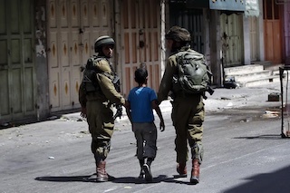 Israeli soldiers apprehend a young Palestinian boy