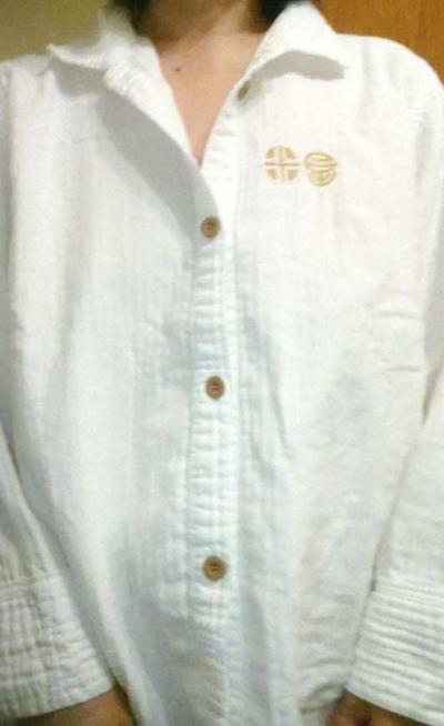 おとぎの宿米屋の金の刺繍でロゴが入った白いパジャマの上半身