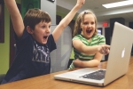 パソコンの画面を見て喜ぶ男の子と女の子の画像